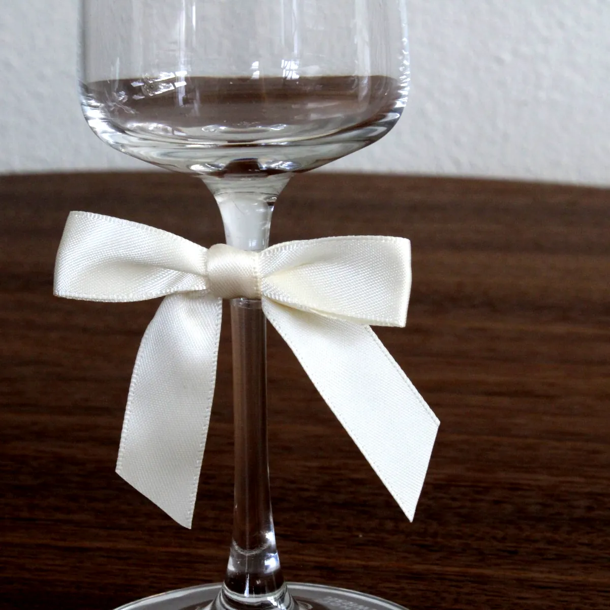 Ivoorkleurig satijnen strikje om de voet van een glas