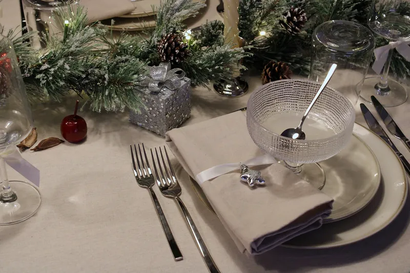 Twee vorken naast een servet met lint en zilveren ster, met de dessertcoupe op het bord