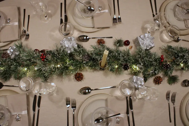 Winter Glow van bovenaf: dennenslinger met lichtjes, dennenappels, rode besjes en zilveren cadeautjes